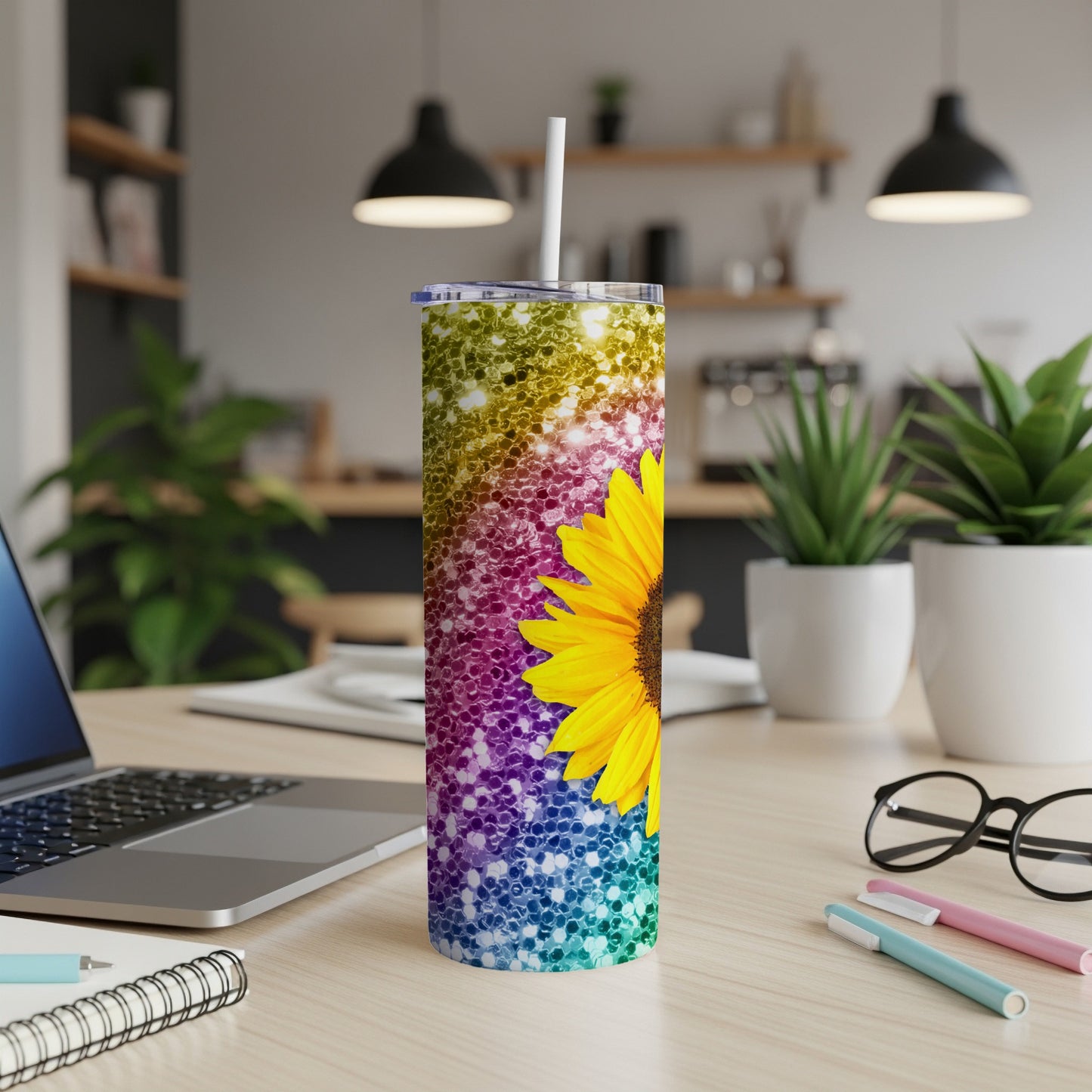 Glittery sunflower tumbler with a white straw on a desk.