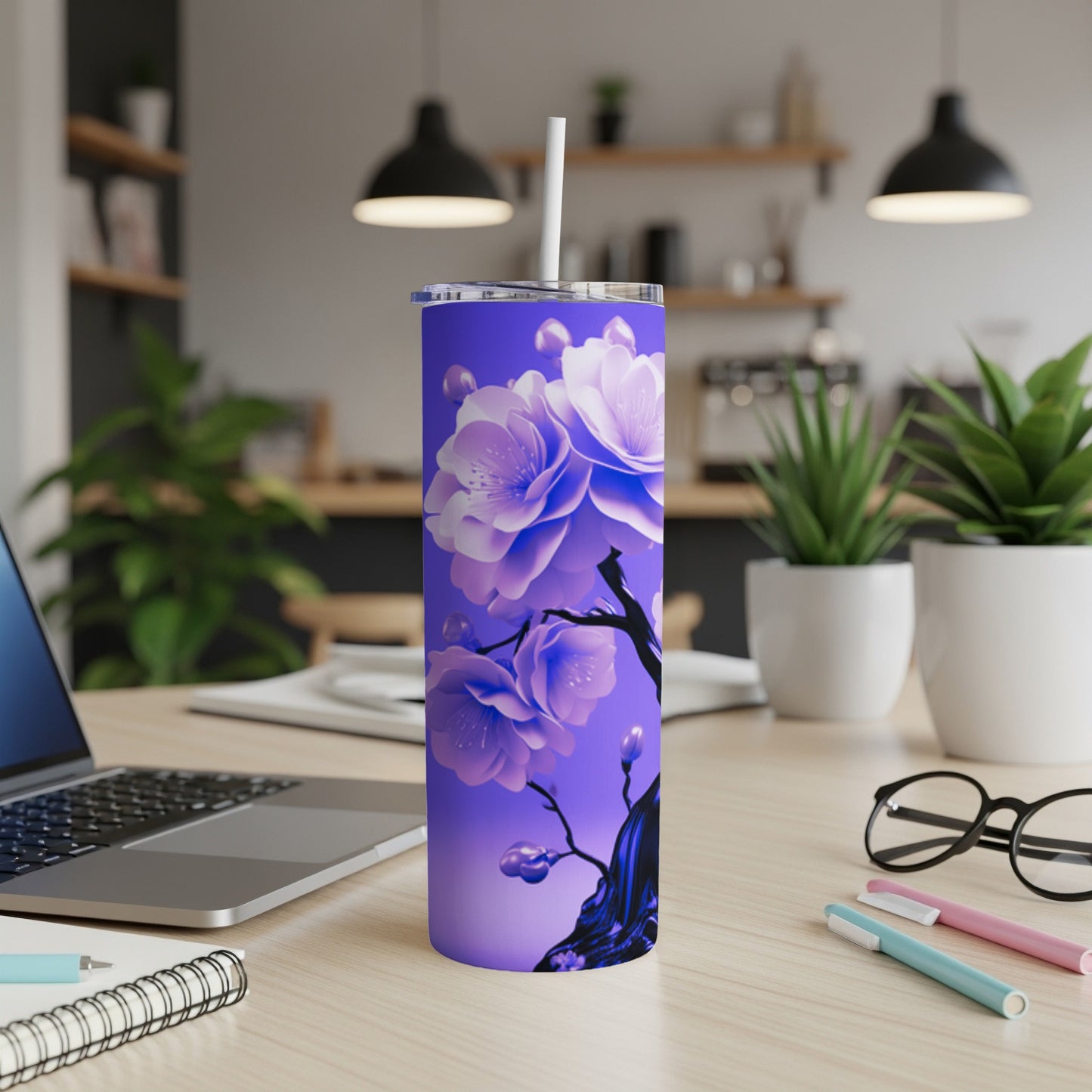 Purple tumbler with blue and pink flowers and a white straw on a desk.
