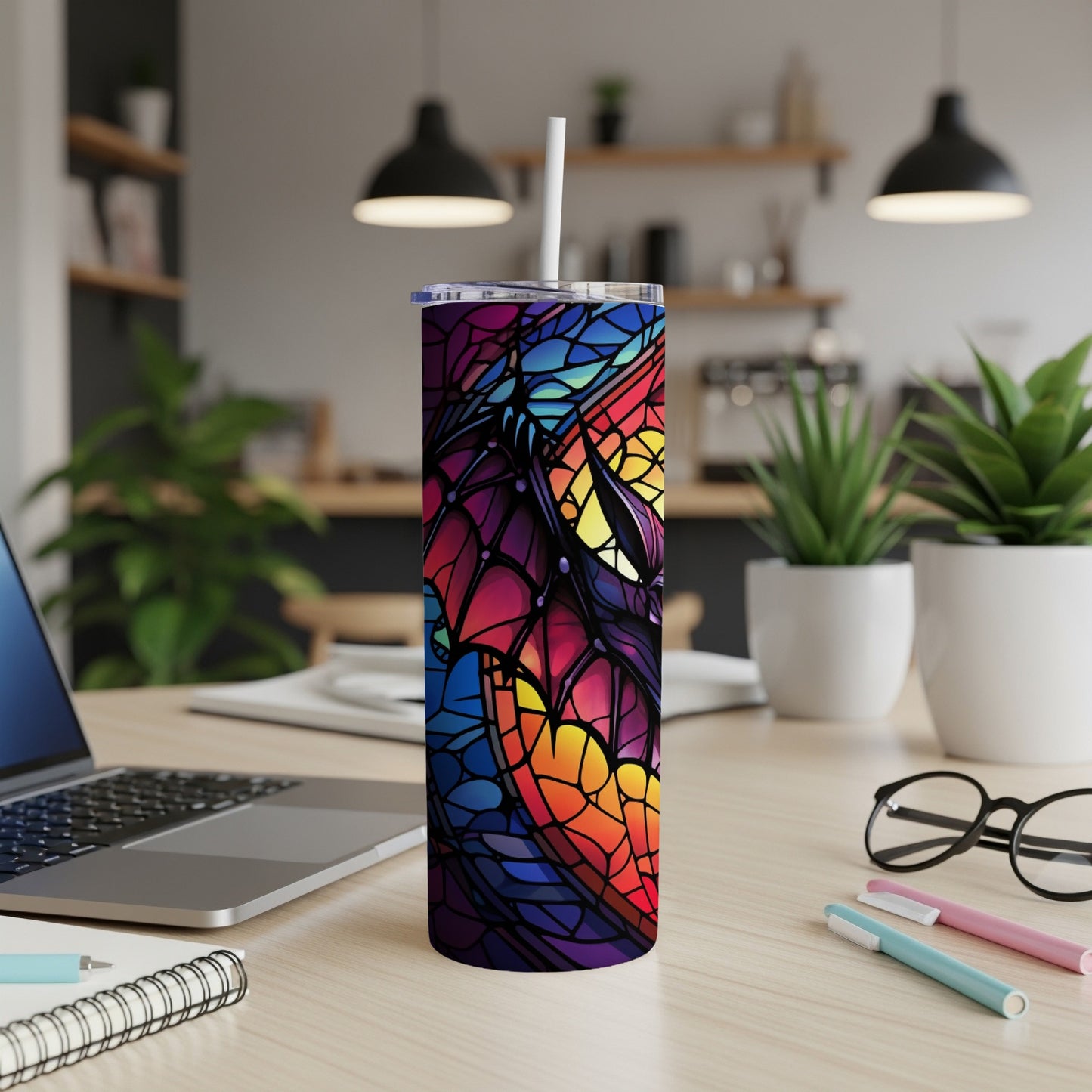 Tall tumbler with stained glass butterfly design, on desk with laptop.