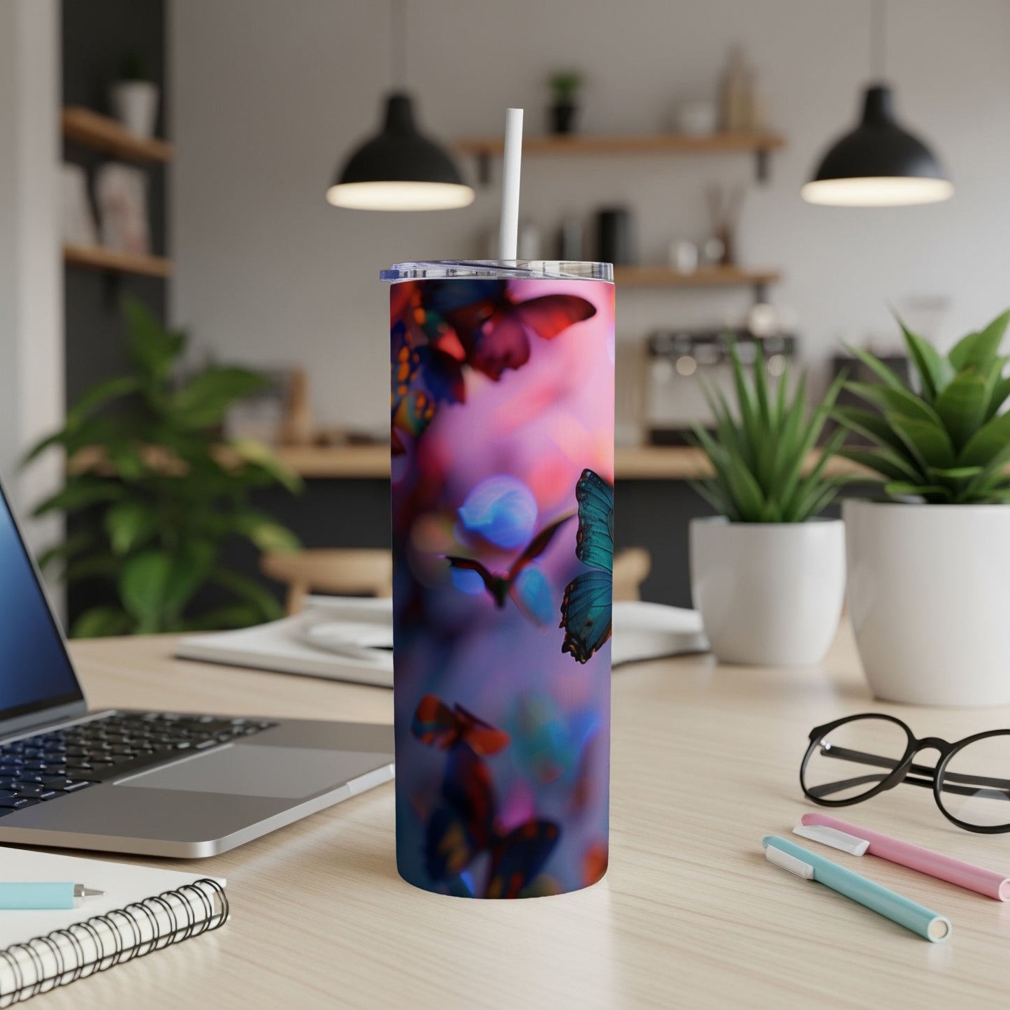Tumbler with colorful butterflies and bokeh lighting on a desk.