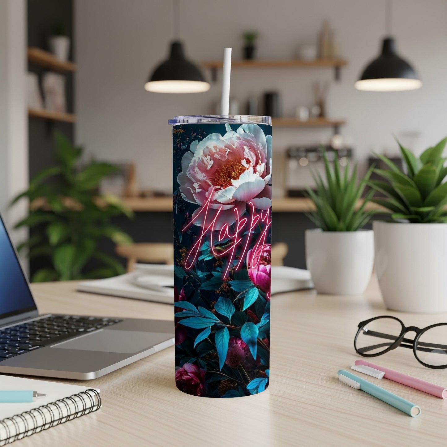 Floral tumbler with neon "Happy" sign on a desk with laptop.