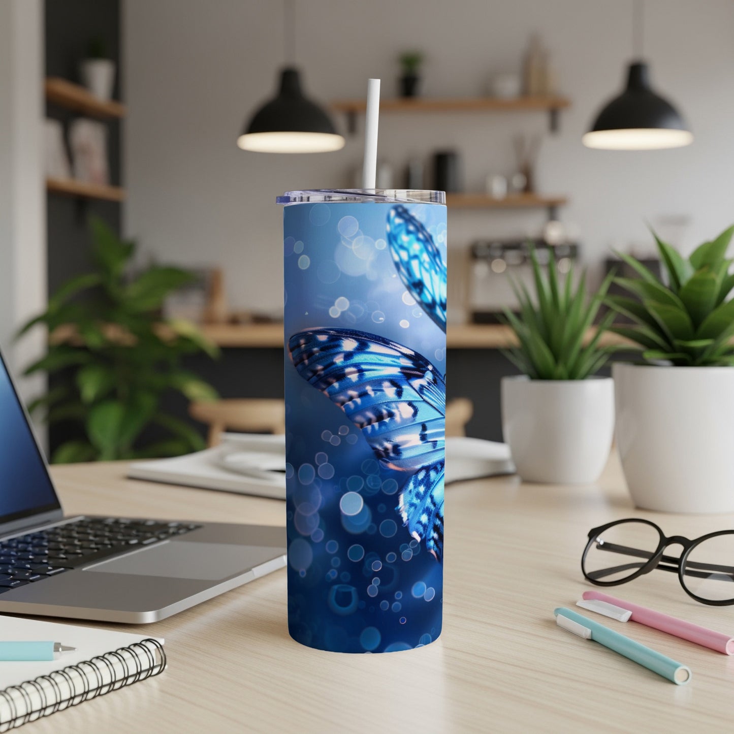 Blue butterfly tumbler with straw on a desk.