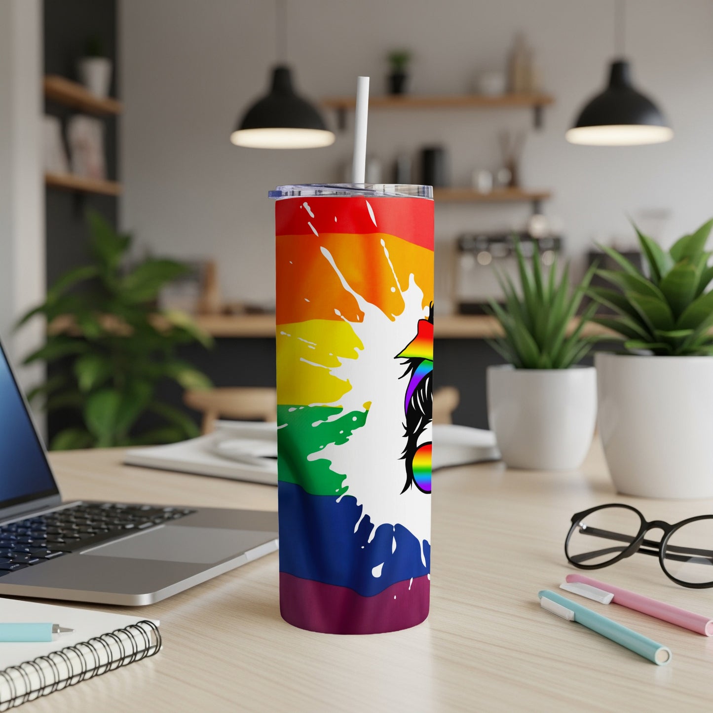 Rainbow gradient tumbler with white unicorn head illustration on a desk.
