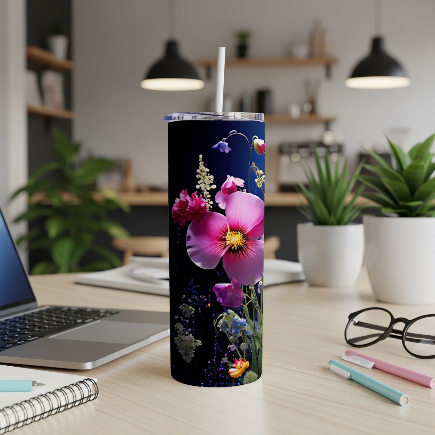 Floral patterned tumbler with flowers on a desk next to a laptop.