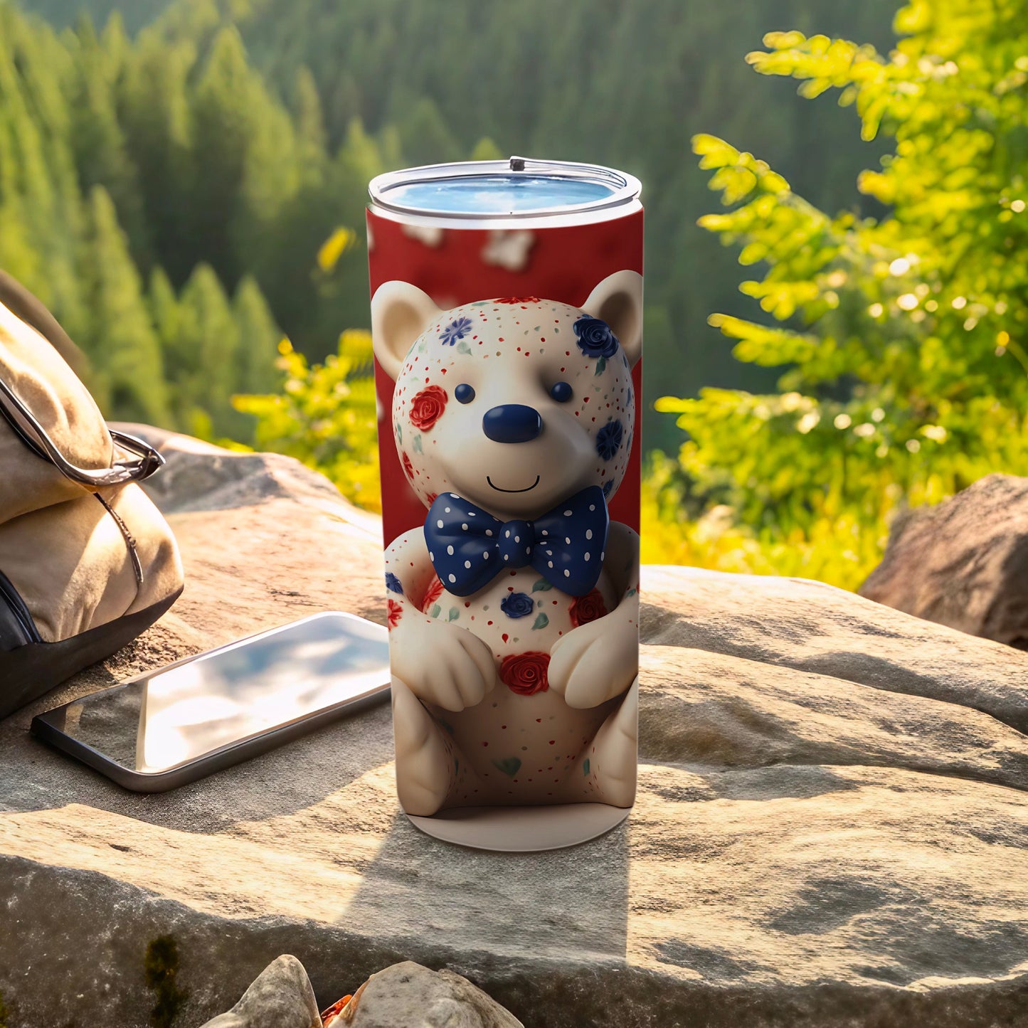 Blue ribbon bear tumbler with floral accents on outdoor rock setting.