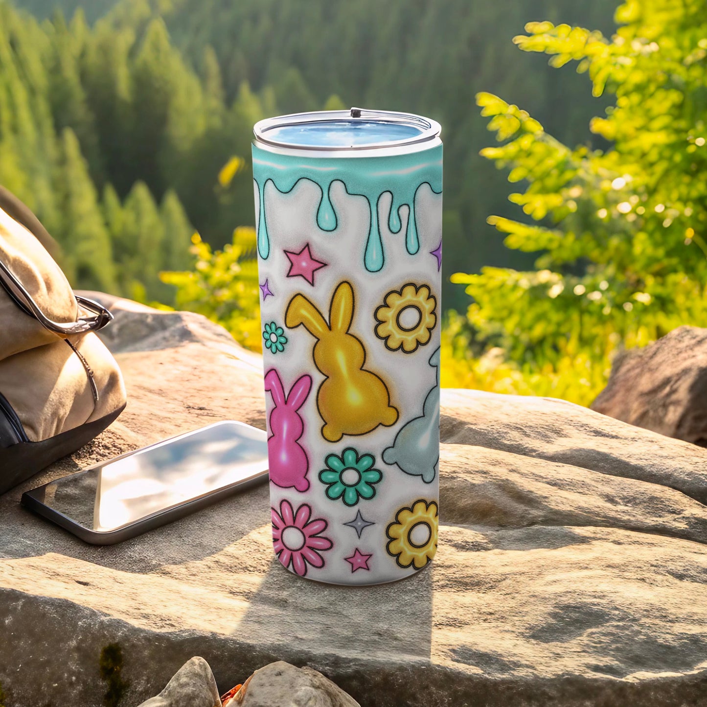 Easter-themed tumbler with bunnies and flowers on a rocky surface.