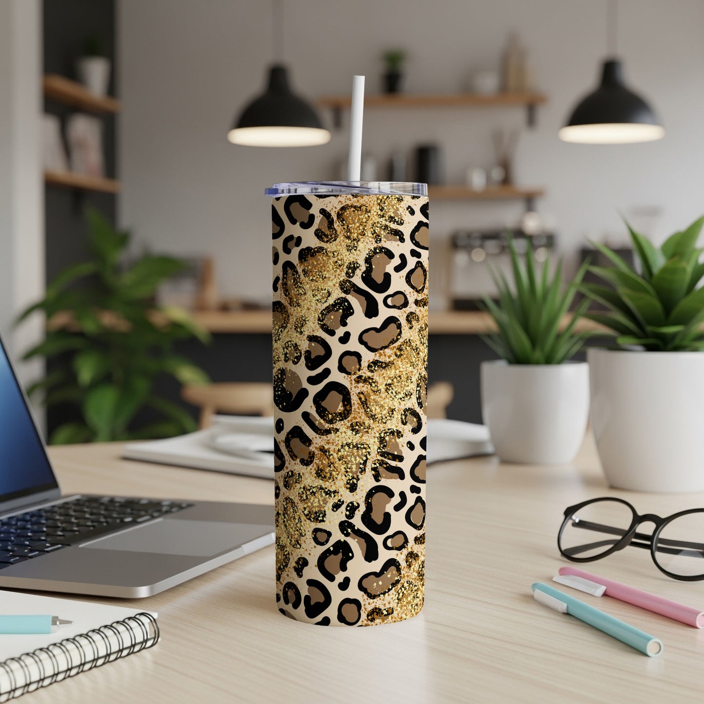 Leopard print tumbler with gold glitter accents on a desk.
