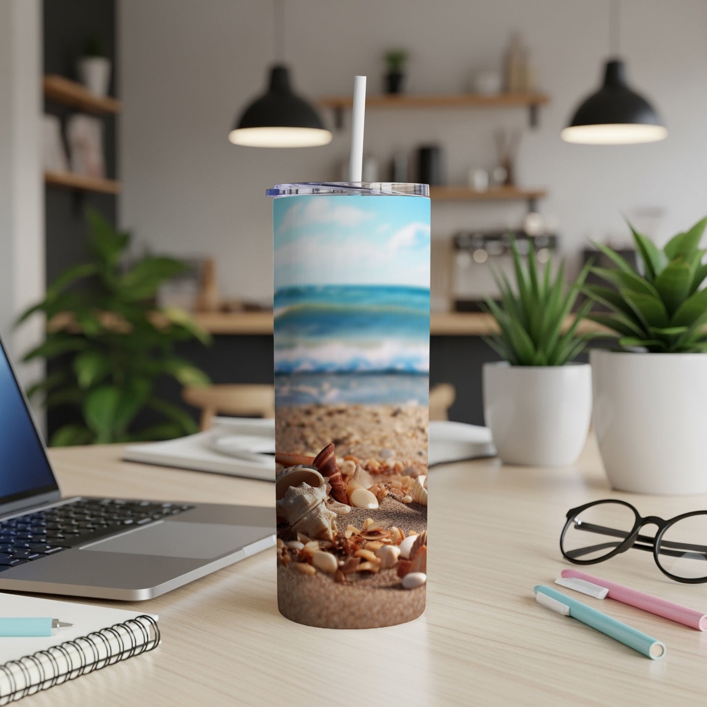 Seashells on a sandy beach with ocean waves, on a travel tumbler.