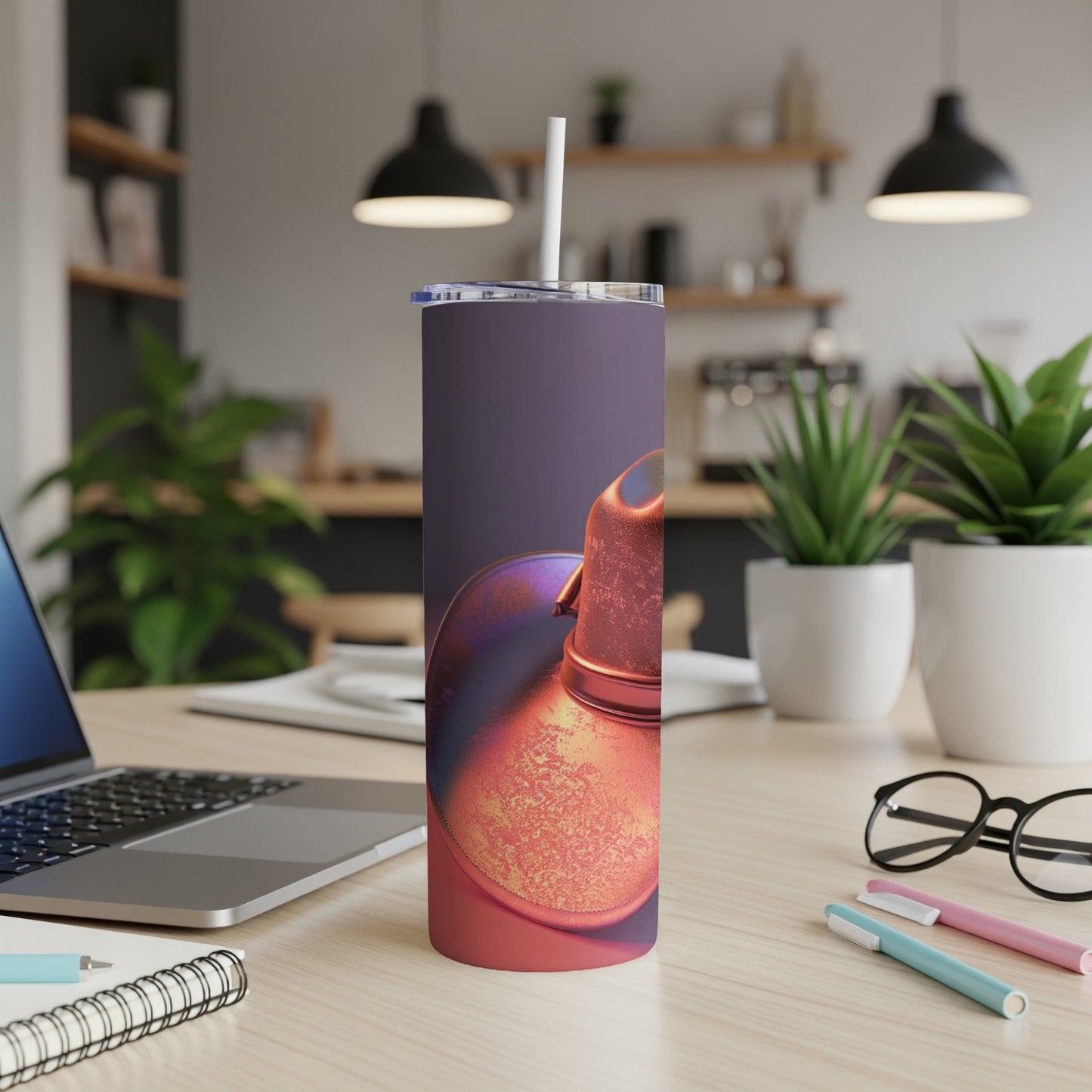 Tumbler with textured orange and purple design sits on a desk next to a laptop.