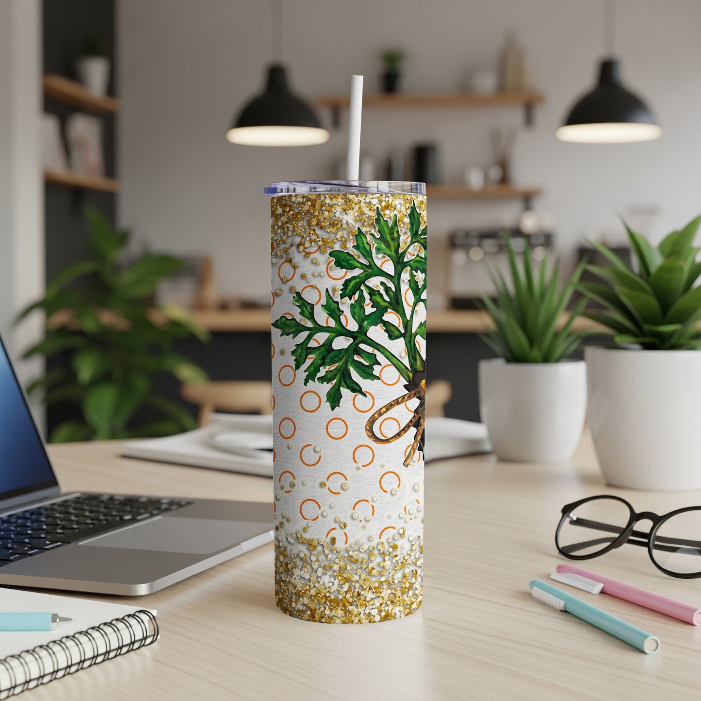 White tumbler with green plant and gold glitter detail on desk.