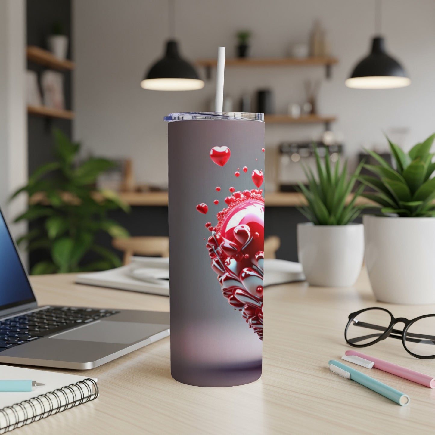 Tumbler with red metallic hearts and a white straw on a desk.