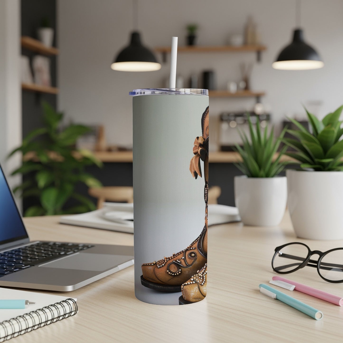 Brown cowboy boot design on a silver tumbler with a straw.