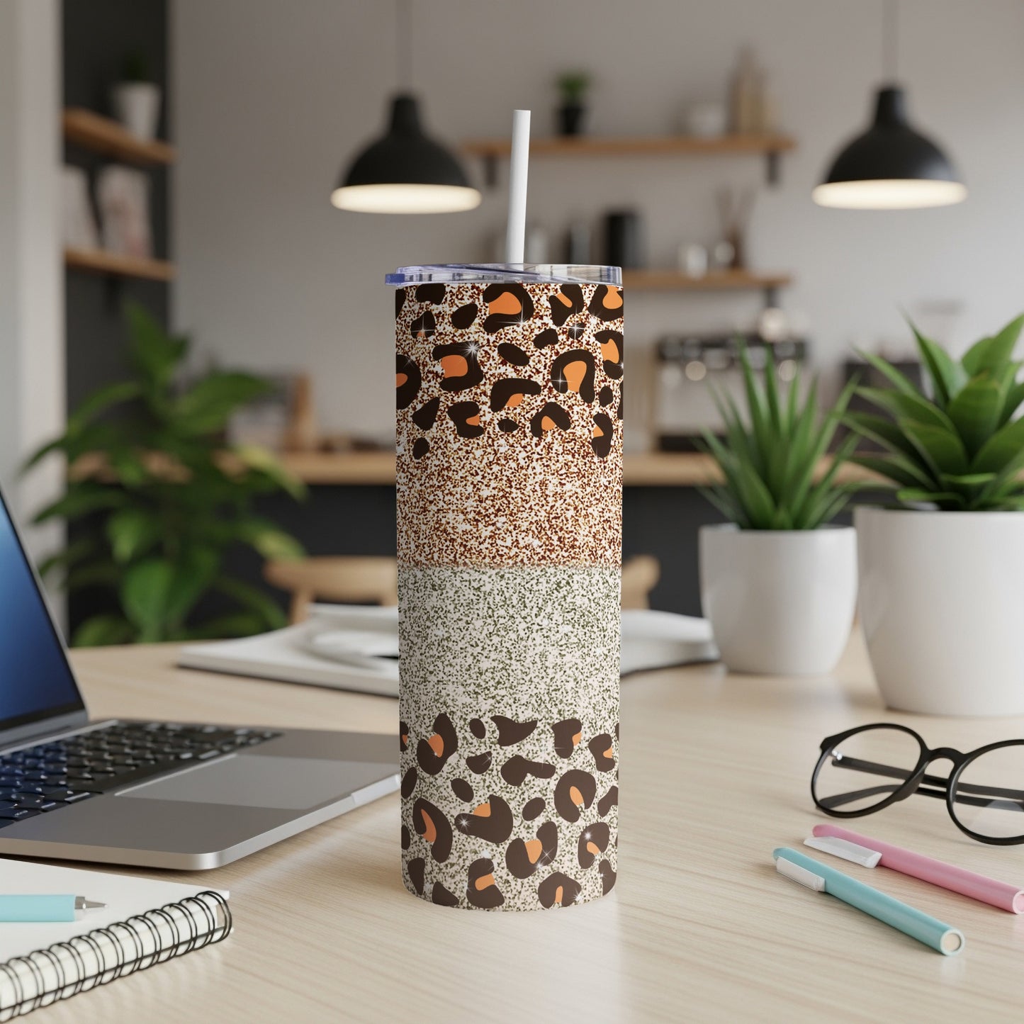 Leopard print and glitter tumbler with a straw on a desk.