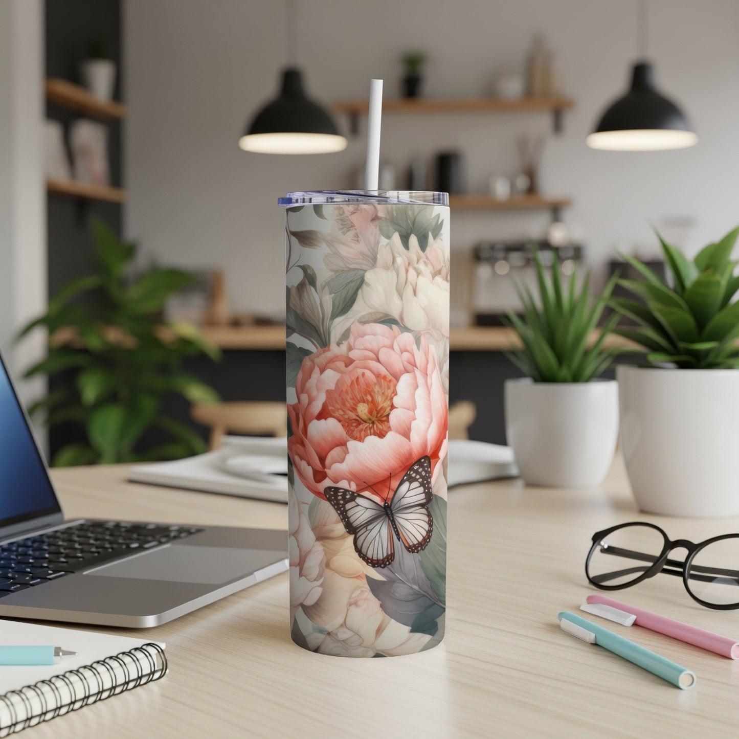 Tall floral tumbler with butterfly design on desk.