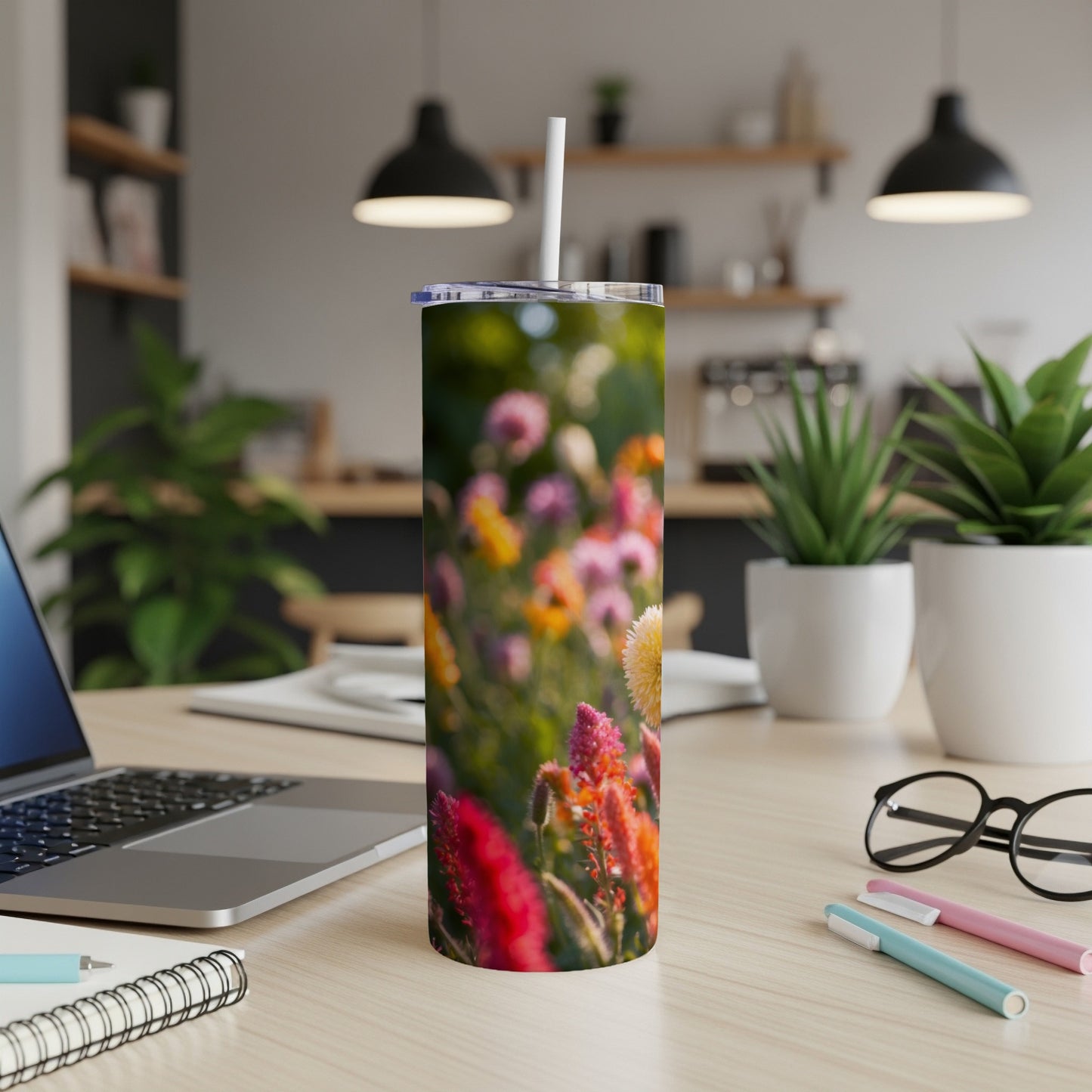 Floral pattern tumbler with straw on a desk beside a laptop.