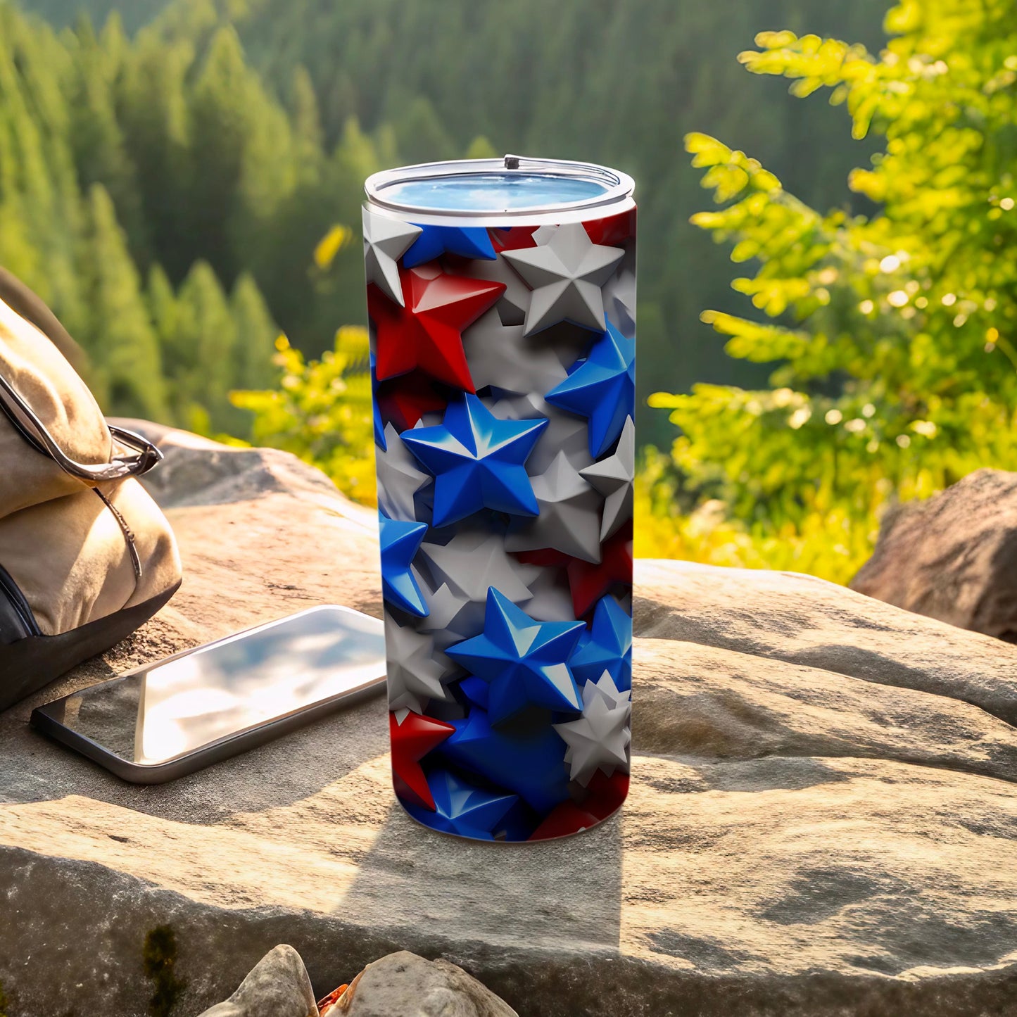 Stars and stripes pattern tumbler with phone and backpack on rock.