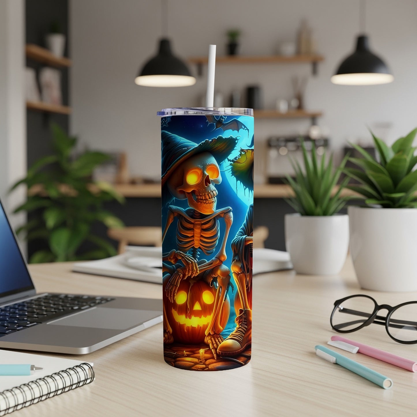 Halloween tumbler with skeleton, pumpkin, and bats on a desk.