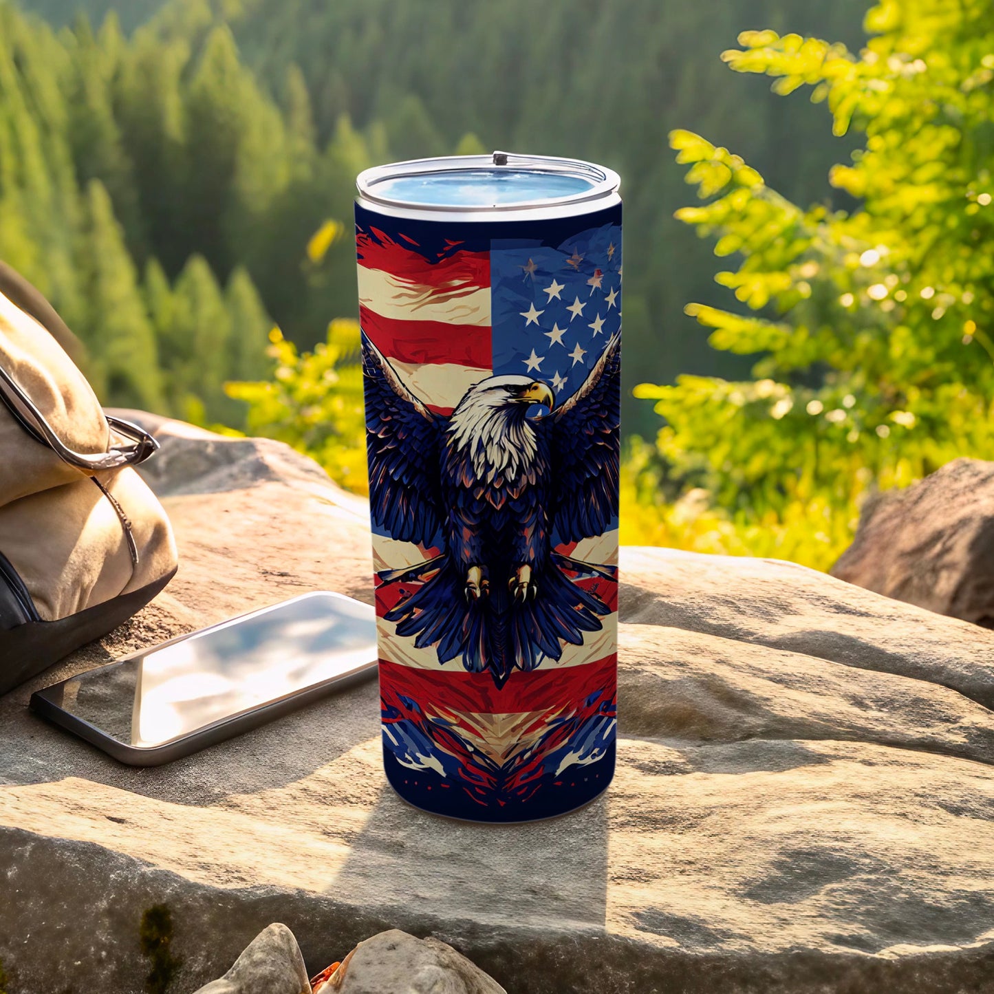 Tumbler with eagle and US flag design sits on rock outdoors.