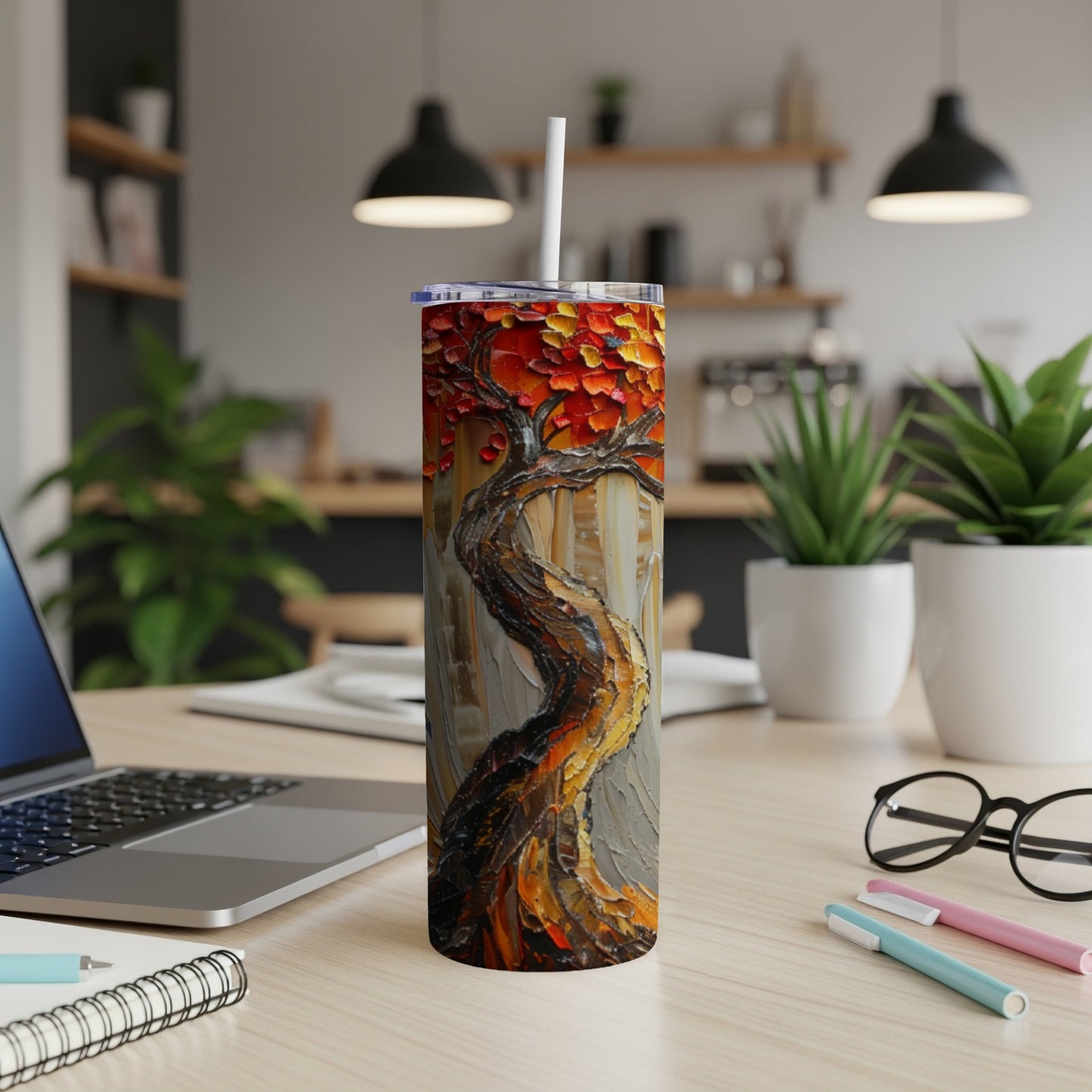 Textured tree artwork on a tumbler with a straw, on a desk.