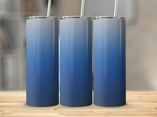 Three blue gradient tumblers with white straws on a wooden surface.