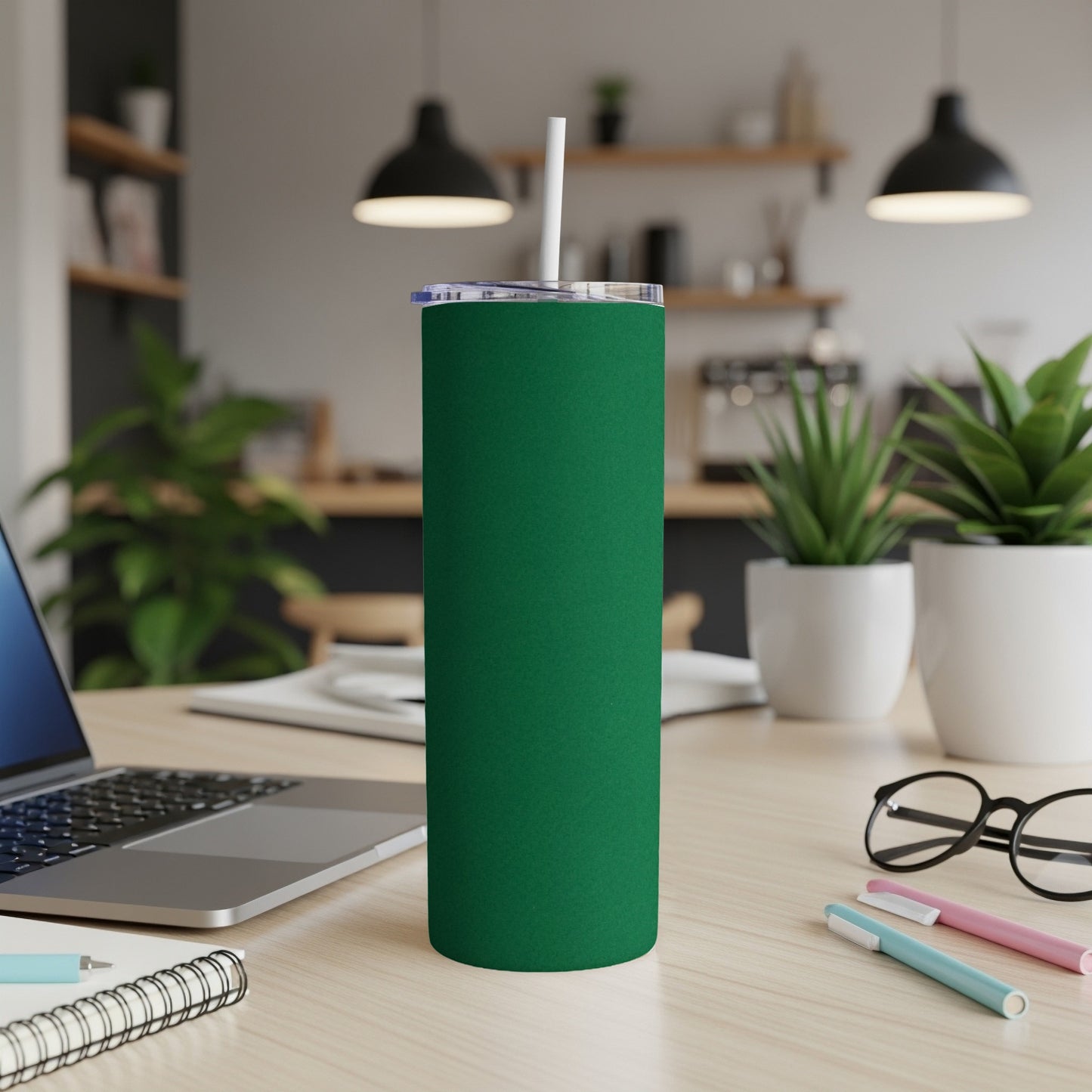 Green tumbler with white lid and straw on a desk.
