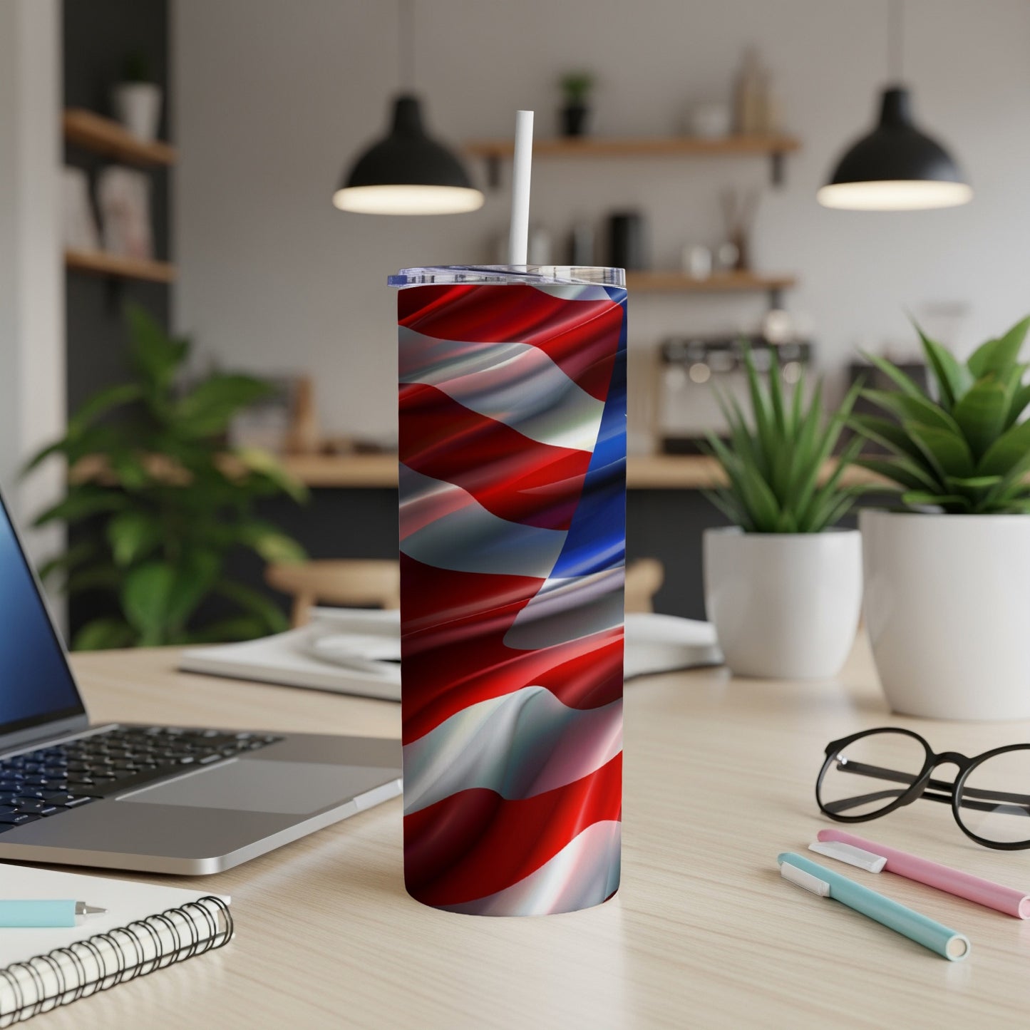 American flag tumbler with straw on a desk with a laptop.