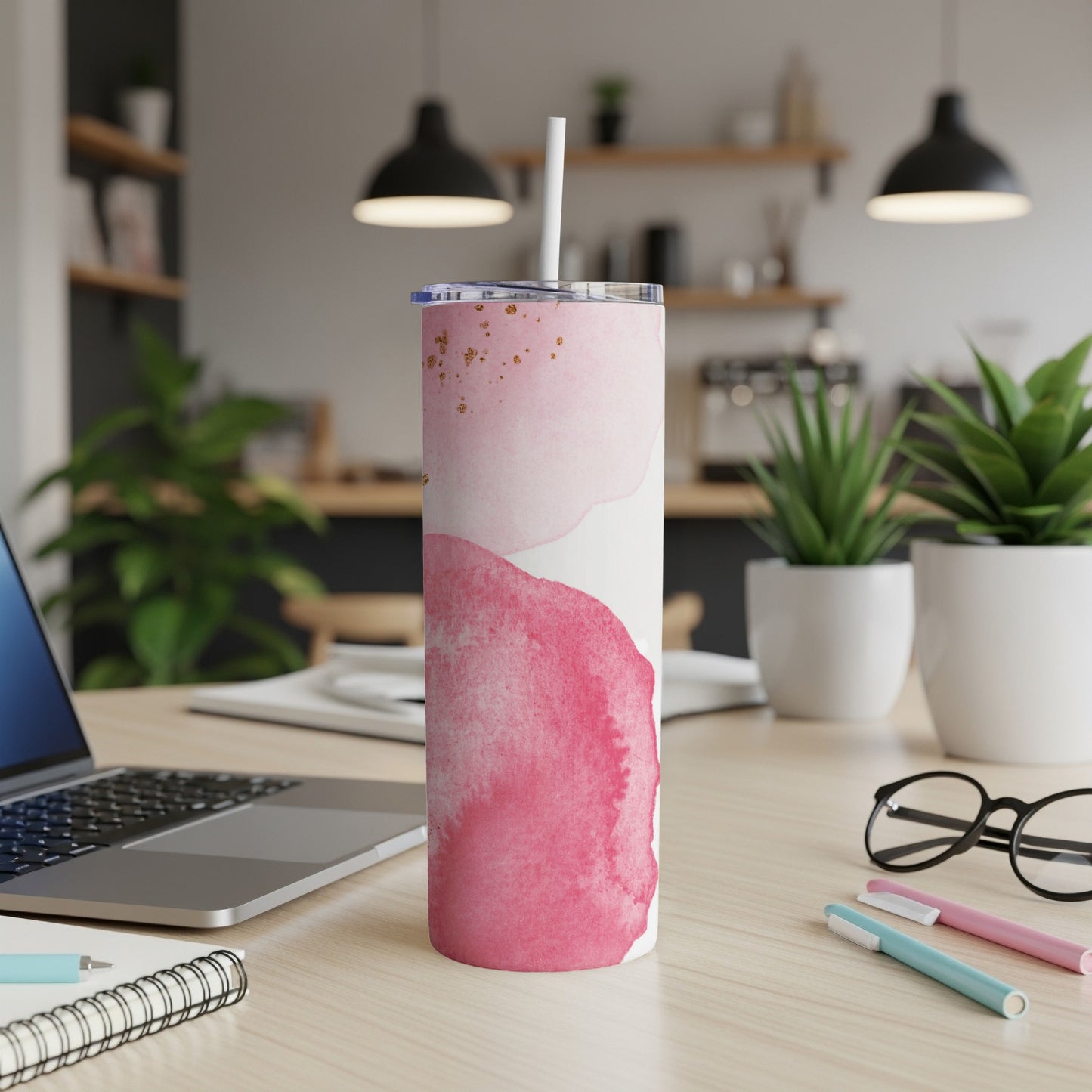 Pink watercolor abstract pattern insulated tumbler with straw on desk.