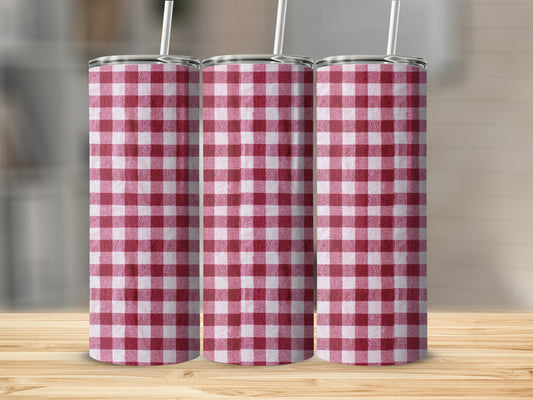 Three tumblers with red and white gingham pattern, standing on a wooden surface.