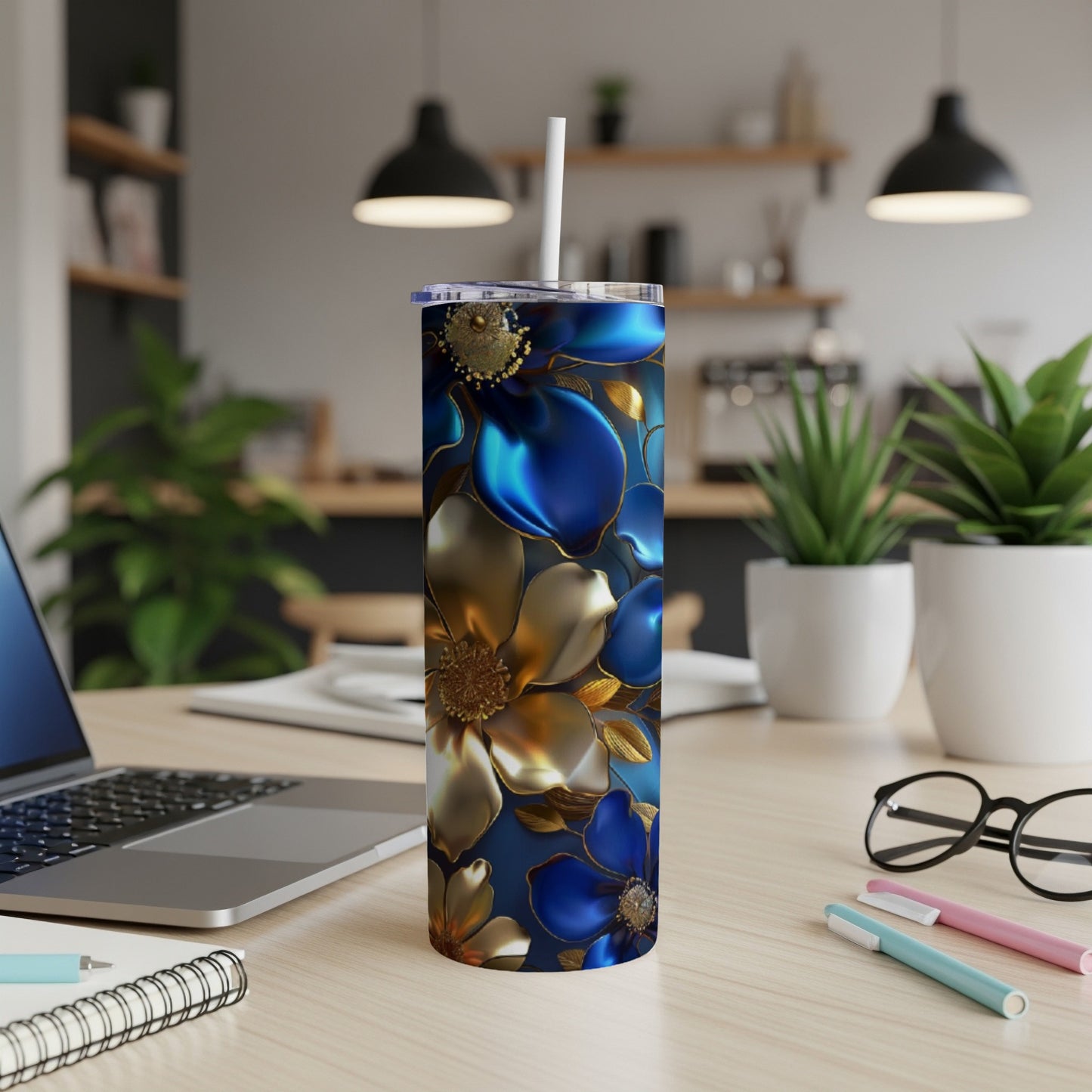 Tall tumbler with blue and gold floral pattern on desk.