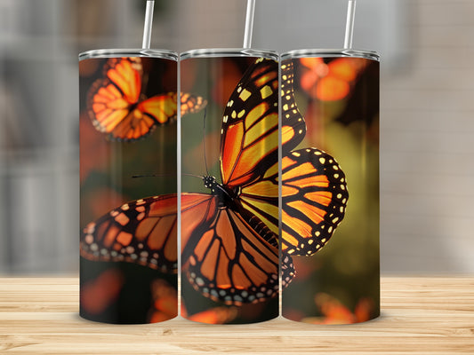 Three tumblers with monarch butterfly design on a wooden surface.