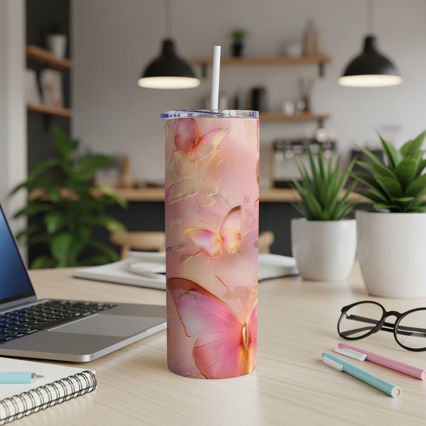 Pink butterfly-patterned tumbler with straw on a desk.