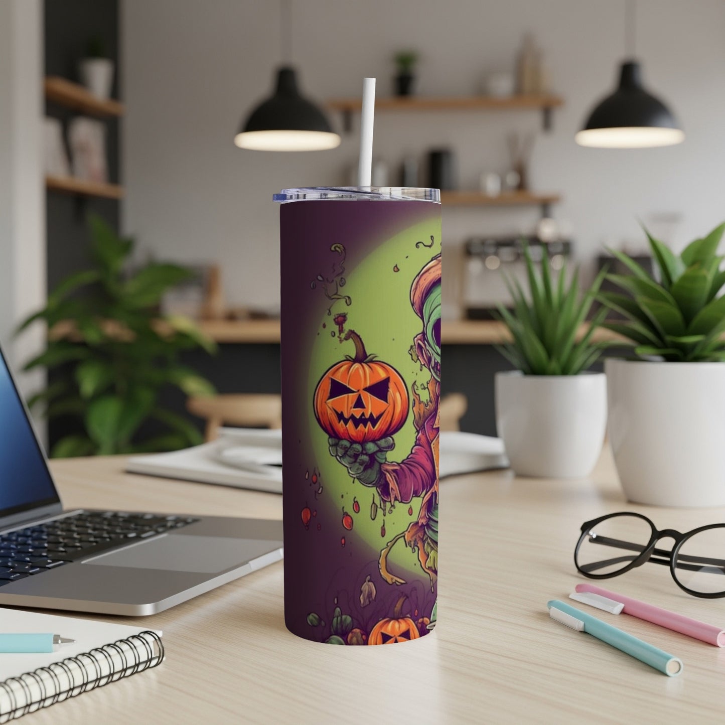 Tall tumbler with Halloween monster holding carved pumpkin and scattered pumpkins.