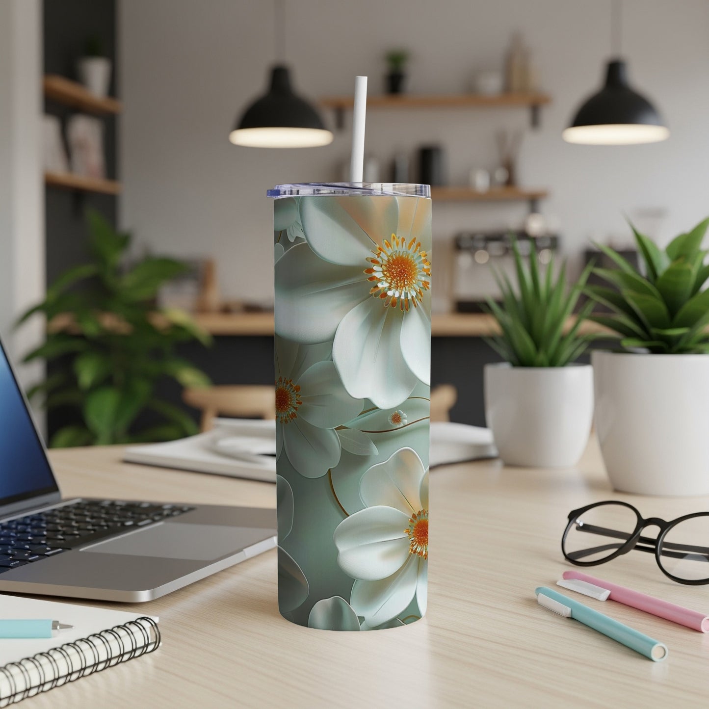 White and pale blue floral pattern tumbler with straw on a desk.