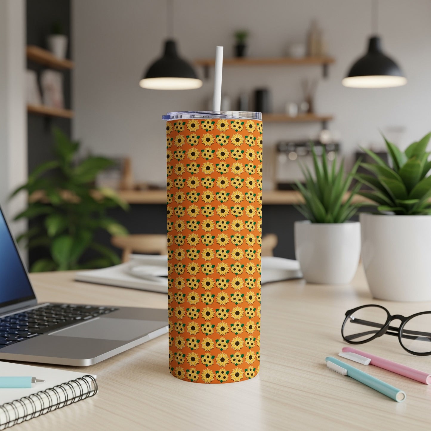 Orange tumbler with a repeating sunflower pattern and white straw.