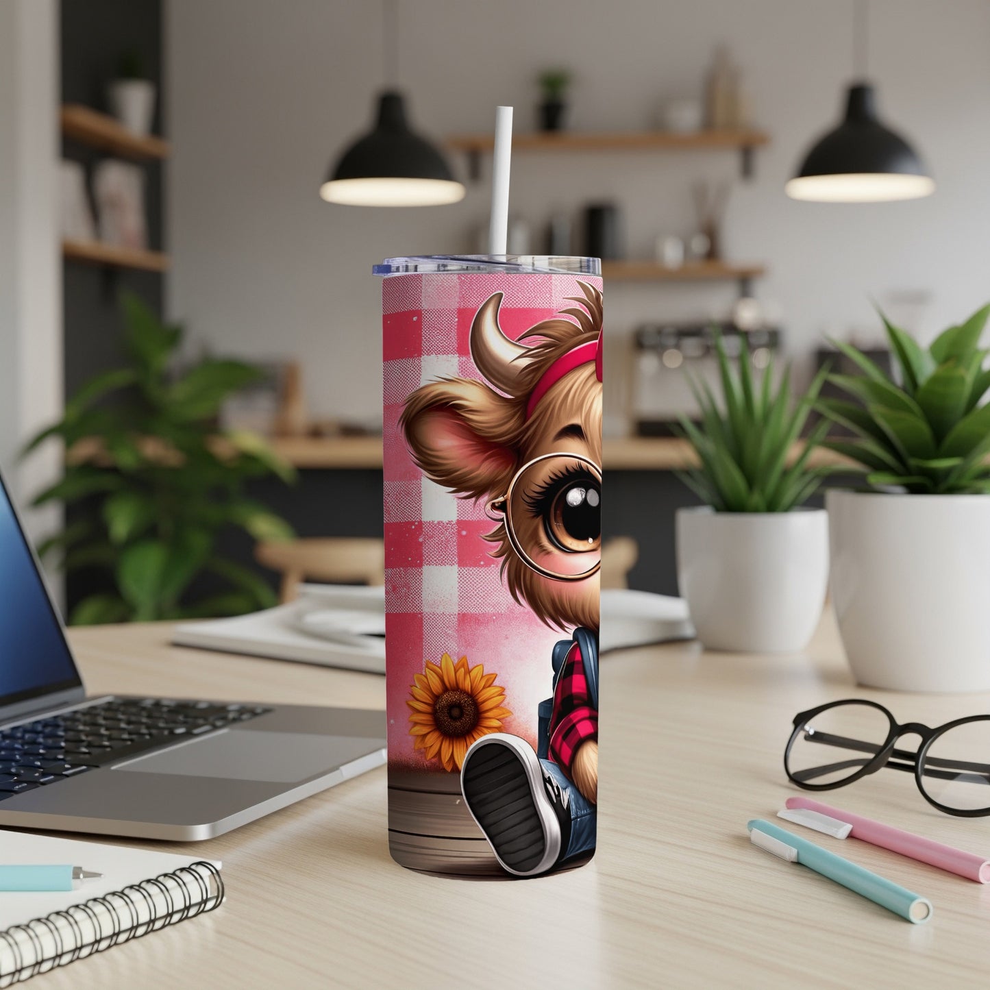 Cow tumbler with sunflower and checkered pattern on desk.