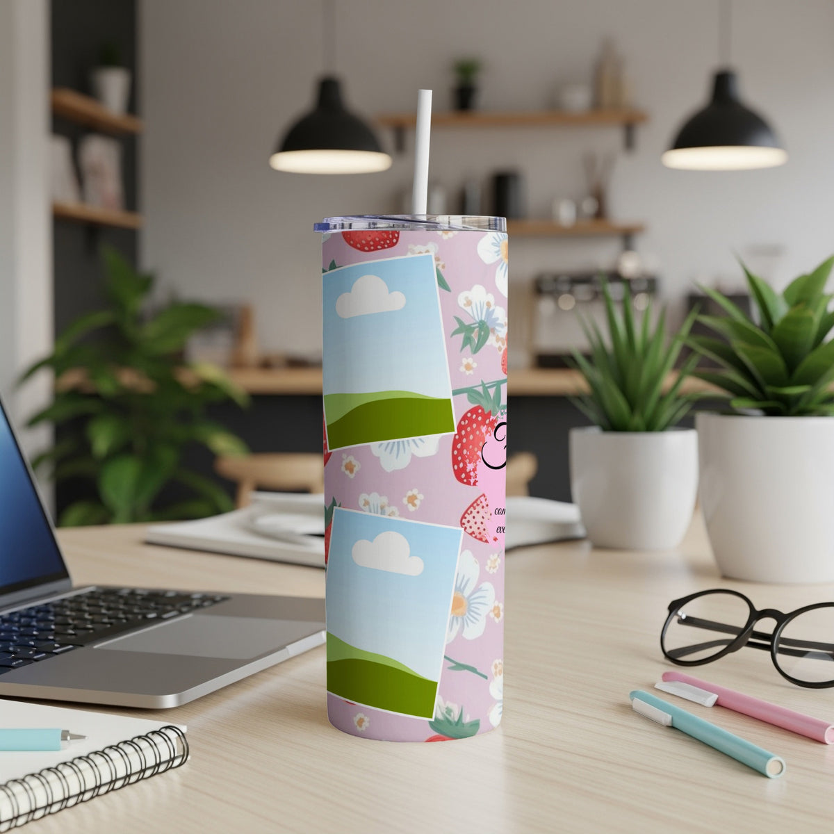Pink tumbler with strawberries, flowers, and photos on a desk with a laptop and glasses.