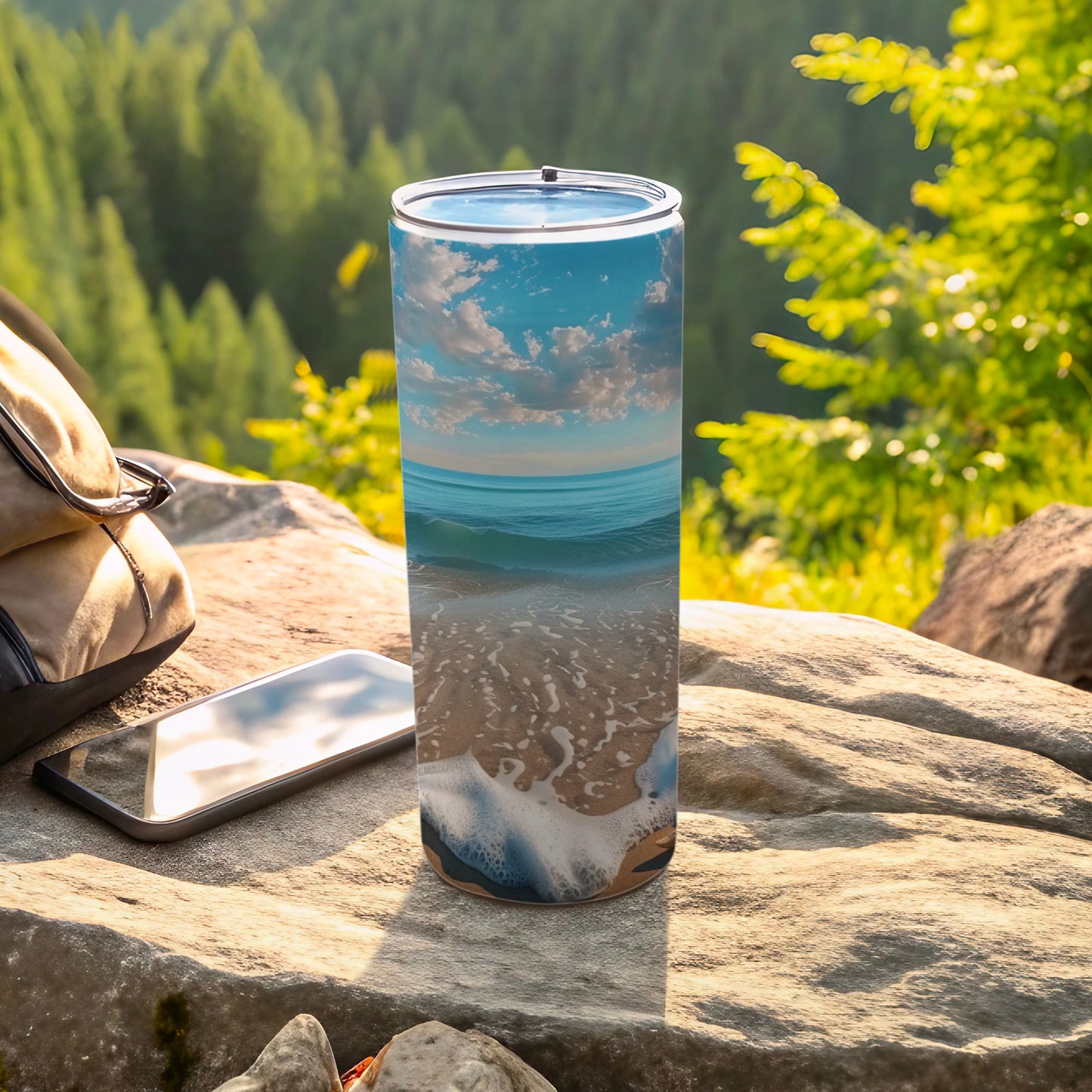 Beach and ocean scene on a tall, insulated tumbler next to a backpack and phone.