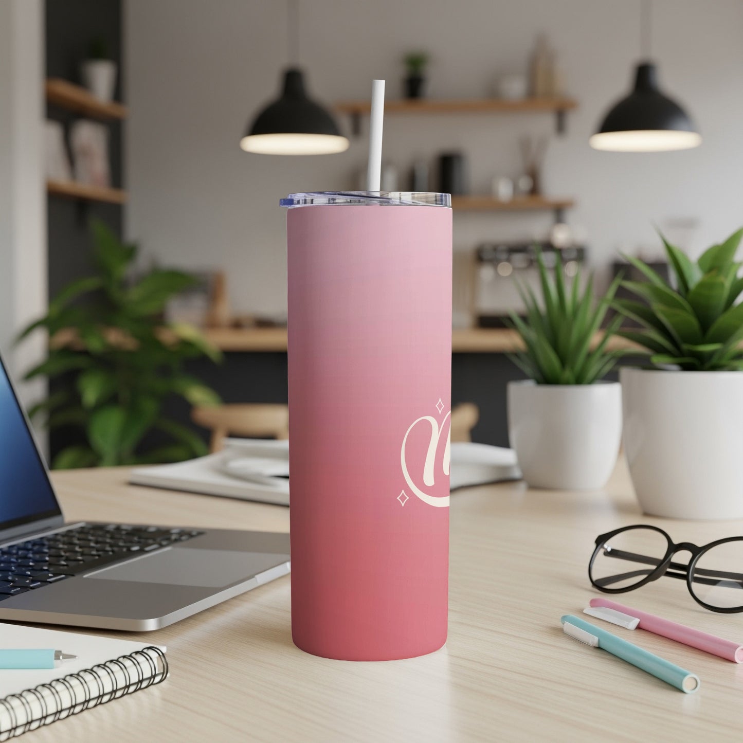 Pink gradient tumbler with white heart design and straw on desk.