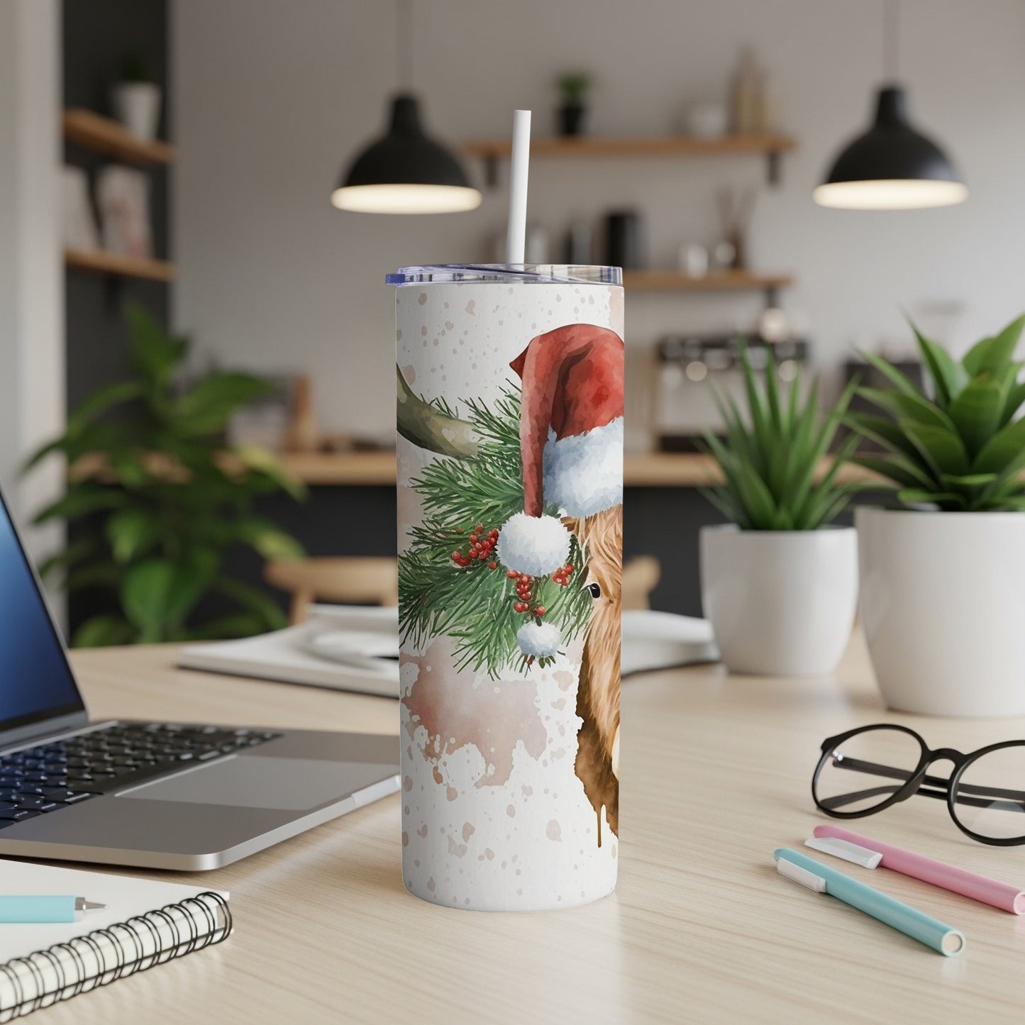 Highland cow in Santa hat with pine branches on a speckled tumbler.
