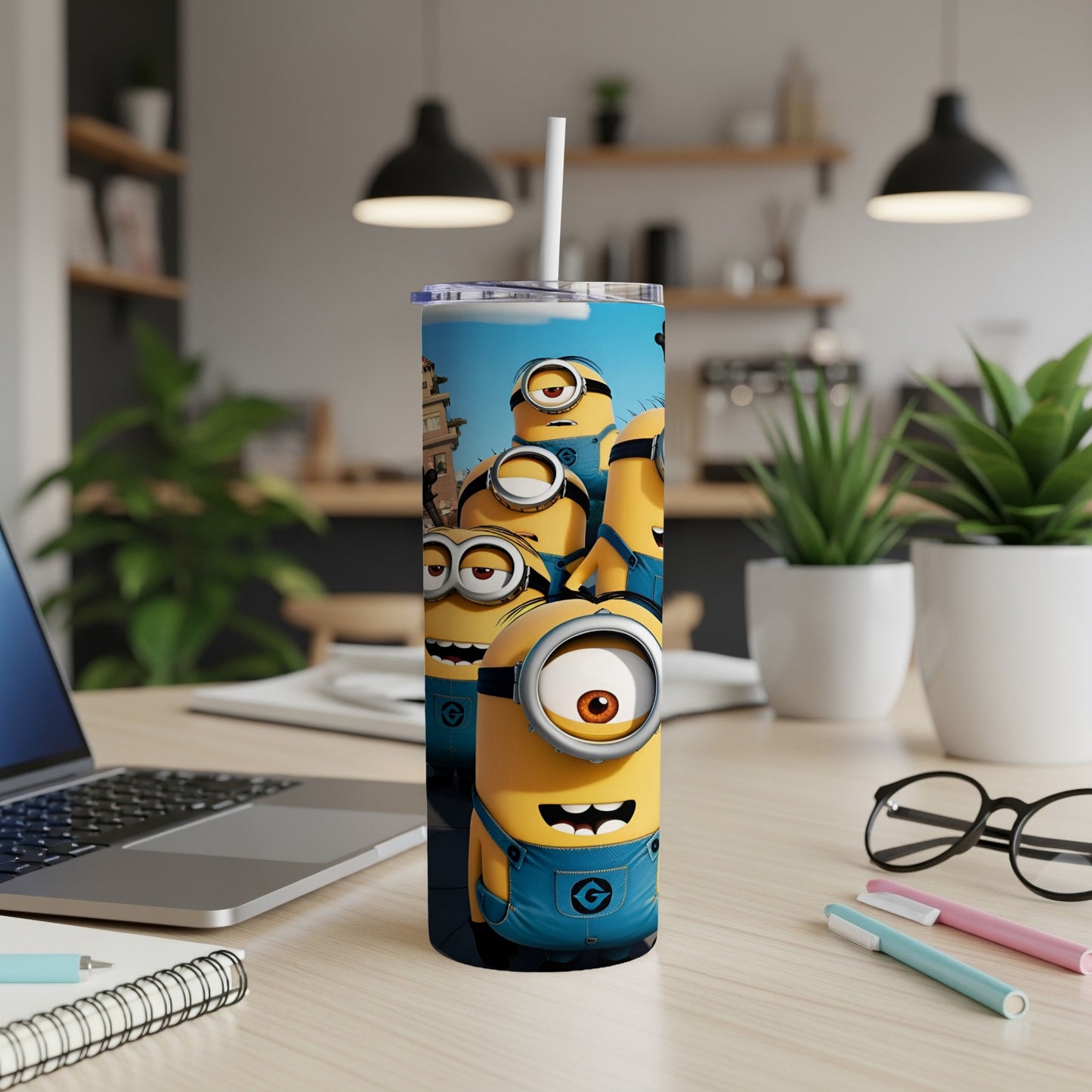 Minions in blue overalls on a tumbler with a straw, on a desk.