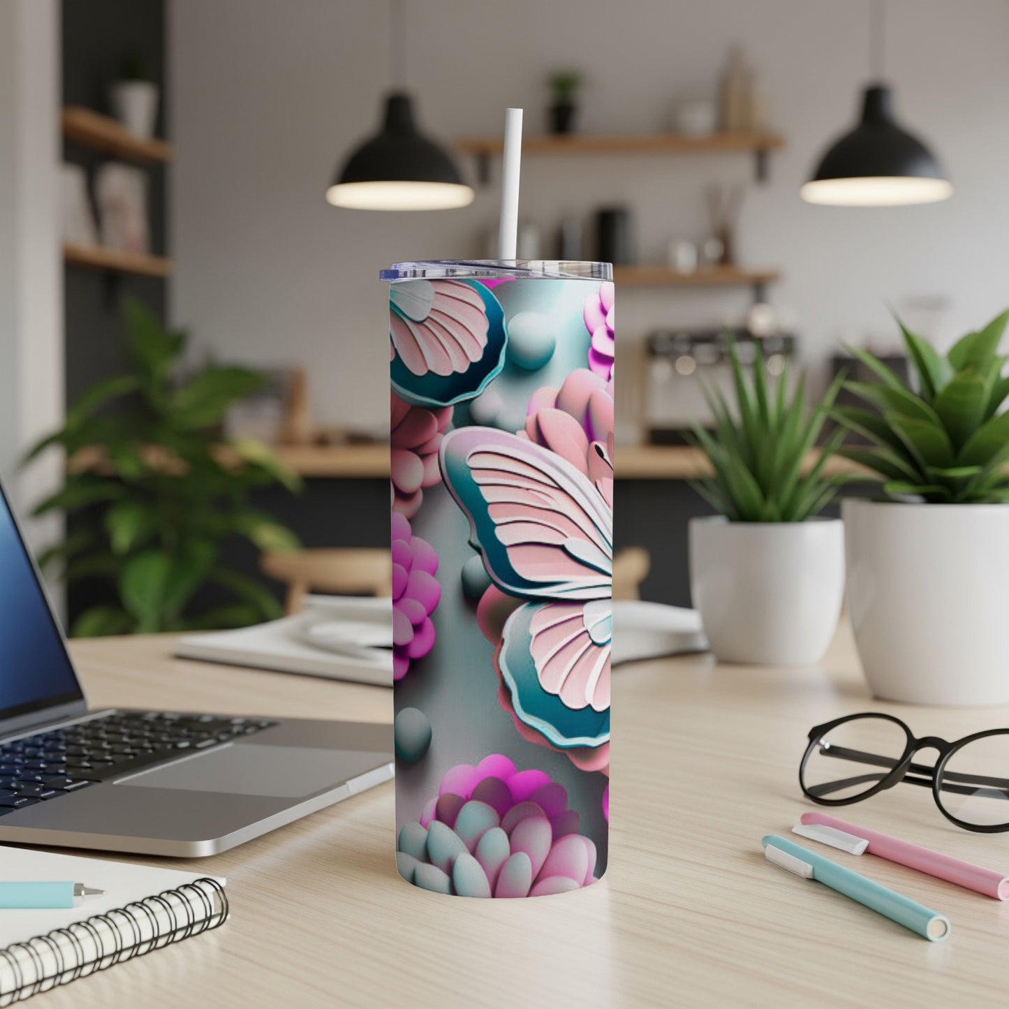 Butterfly and floral patterned tumbler with straw on desk.
