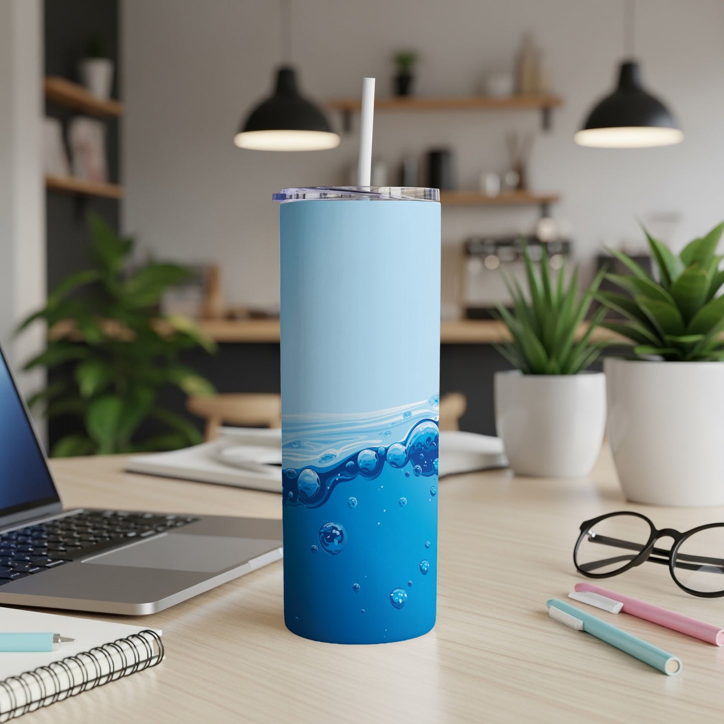 Blue and white tumbler with water bubbles graphic, straw inserted, on a desk.