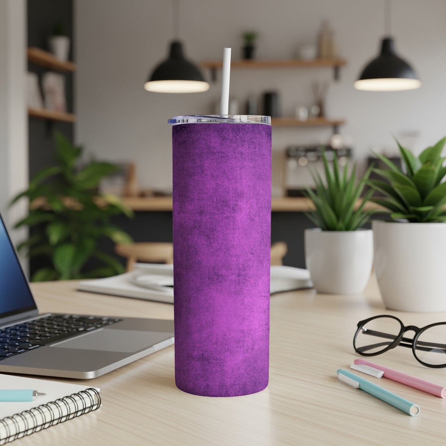 Purple textured tumbler with a straw on a desk next to a laptop.