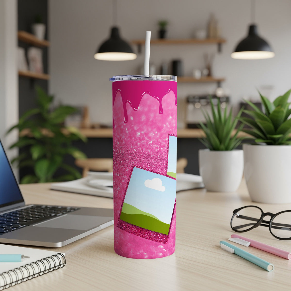Pink glitter tumbler with dripping paint design and framed landscape images.