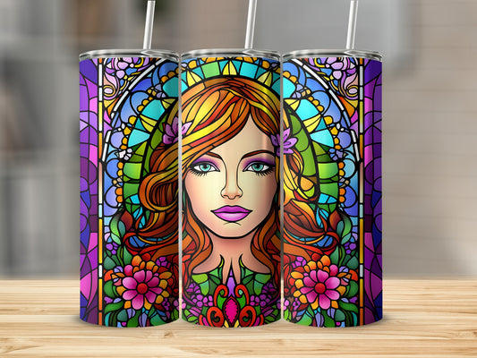 Stained glass tumbler with woman's face surrounded by floral and geometric patterns.