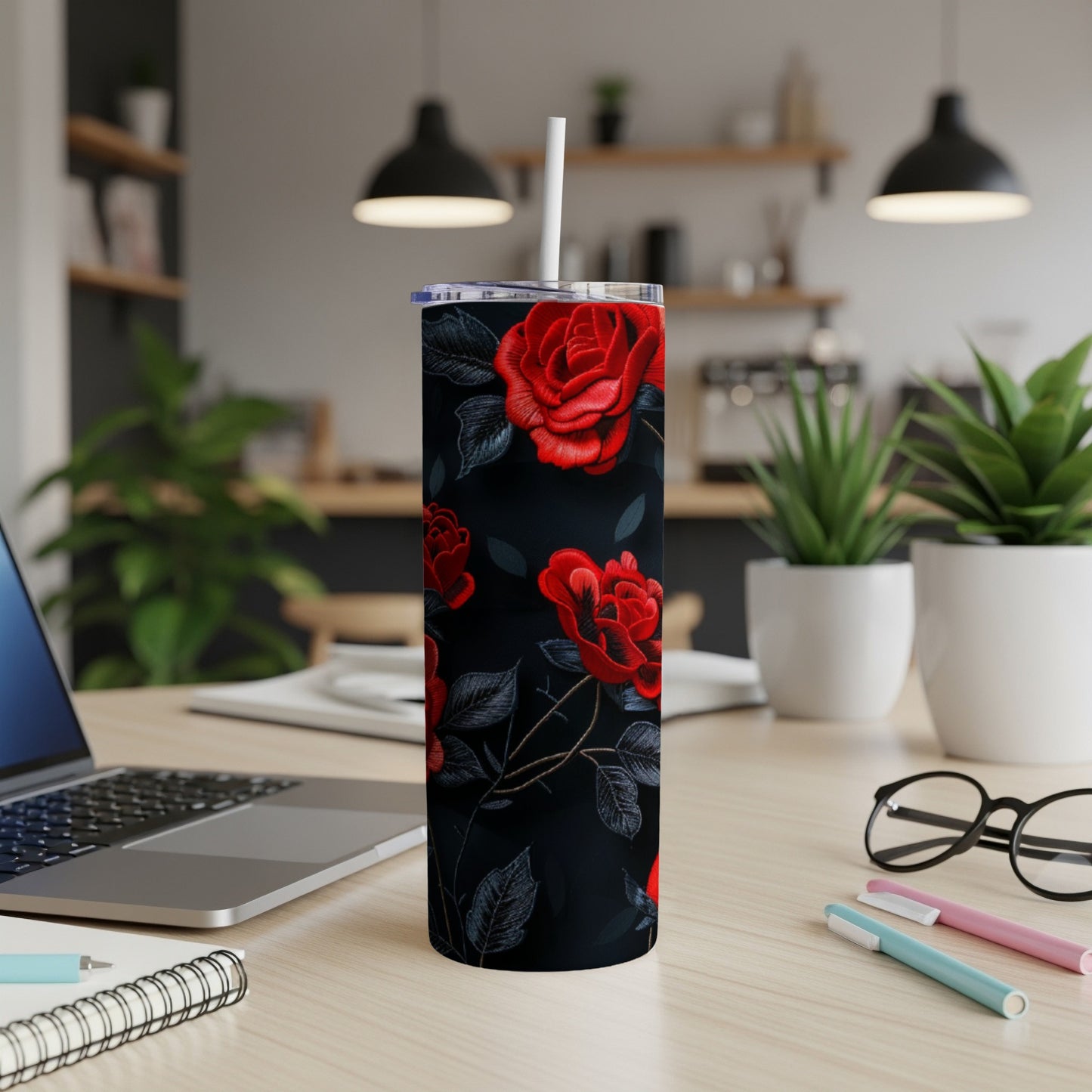 Red roses on a dark floral pattern tumbler with a white straw.