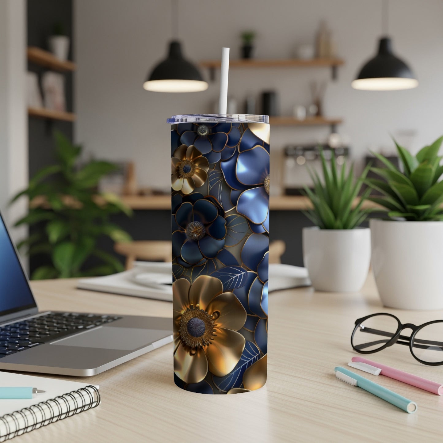 Blue and gold floral pattern insulated tumbler with straw on desk.
