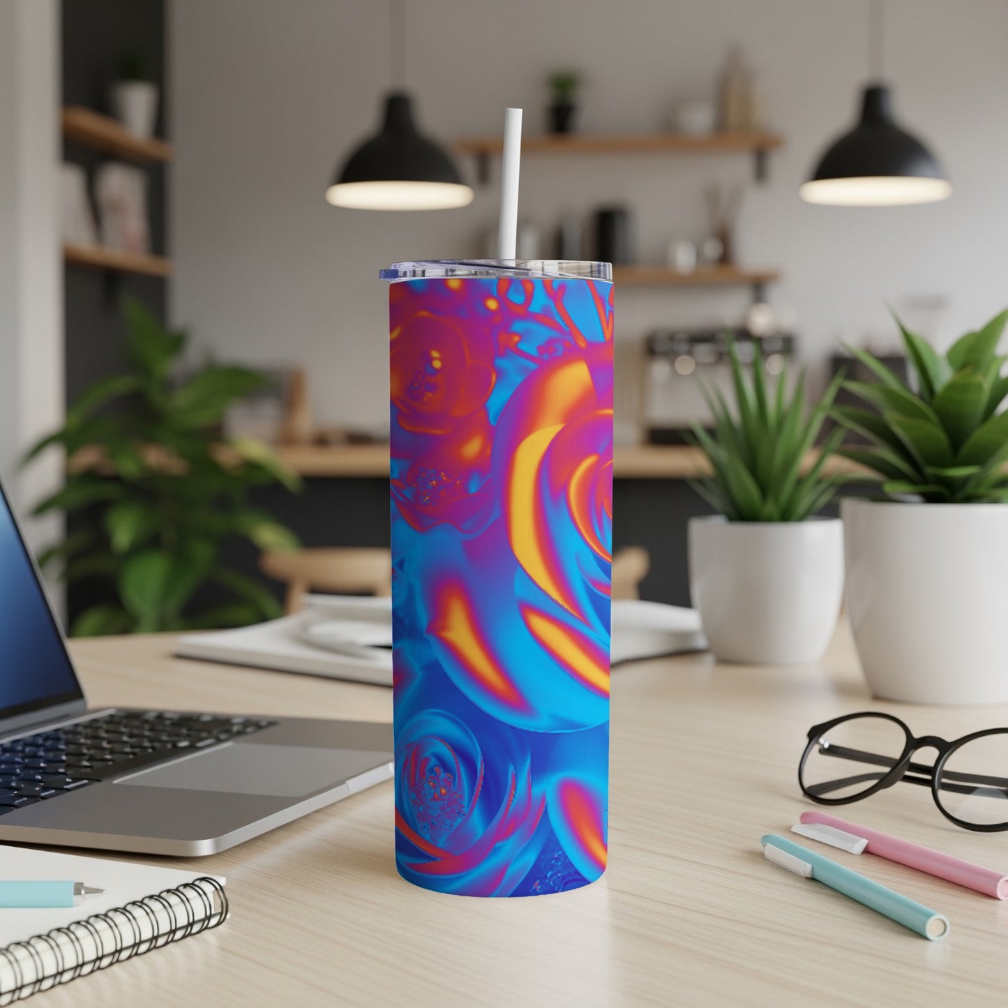 Blue and pink floral pattern tumbler with straw on a desk.