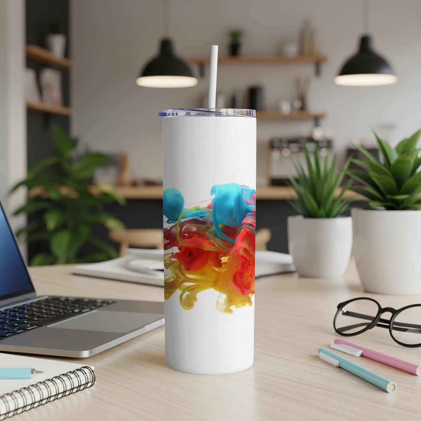 White tumbler with colorful ink swirls, on a desk.