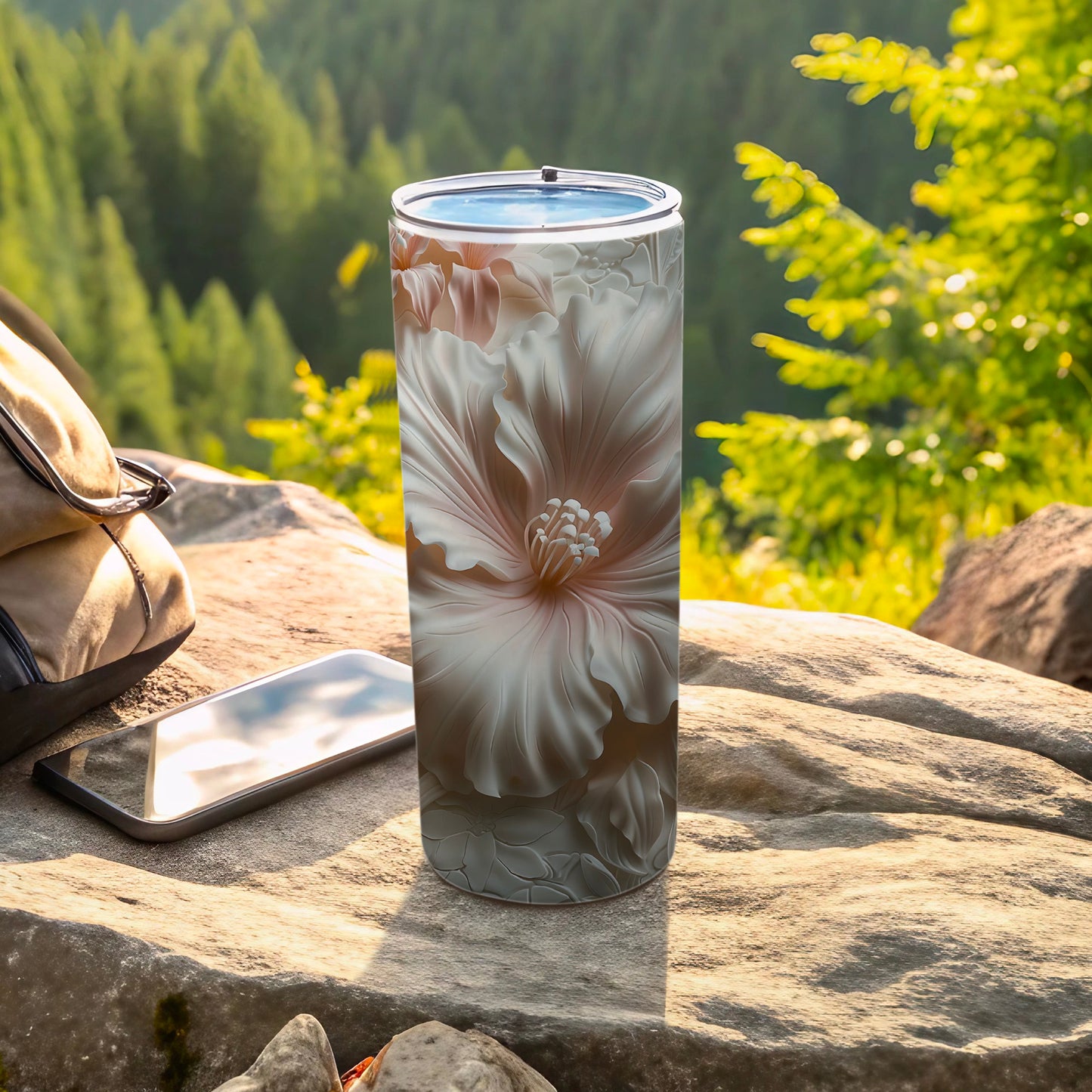 Floral patterned tumbler with smartphone and backpack on rocks.